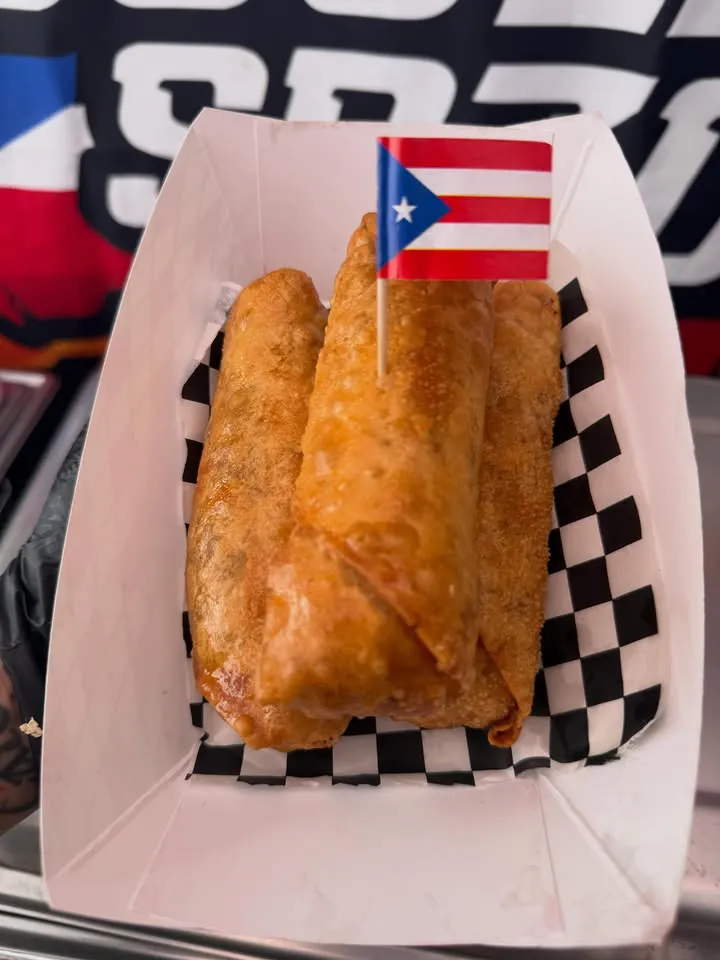Fried rolls in a paper boat lined with checkered paper, a small Puerto Rican flag on a pick.